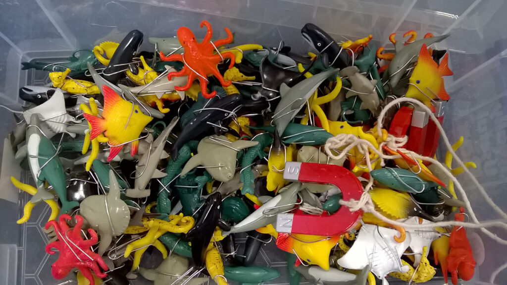plastic toy sea creatures in a storage tub with a horse-show shaped magnet on top of them